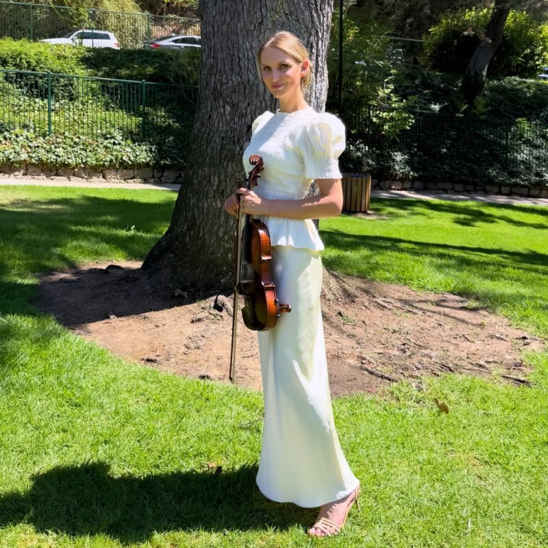 Mila with her violin under a garden tree