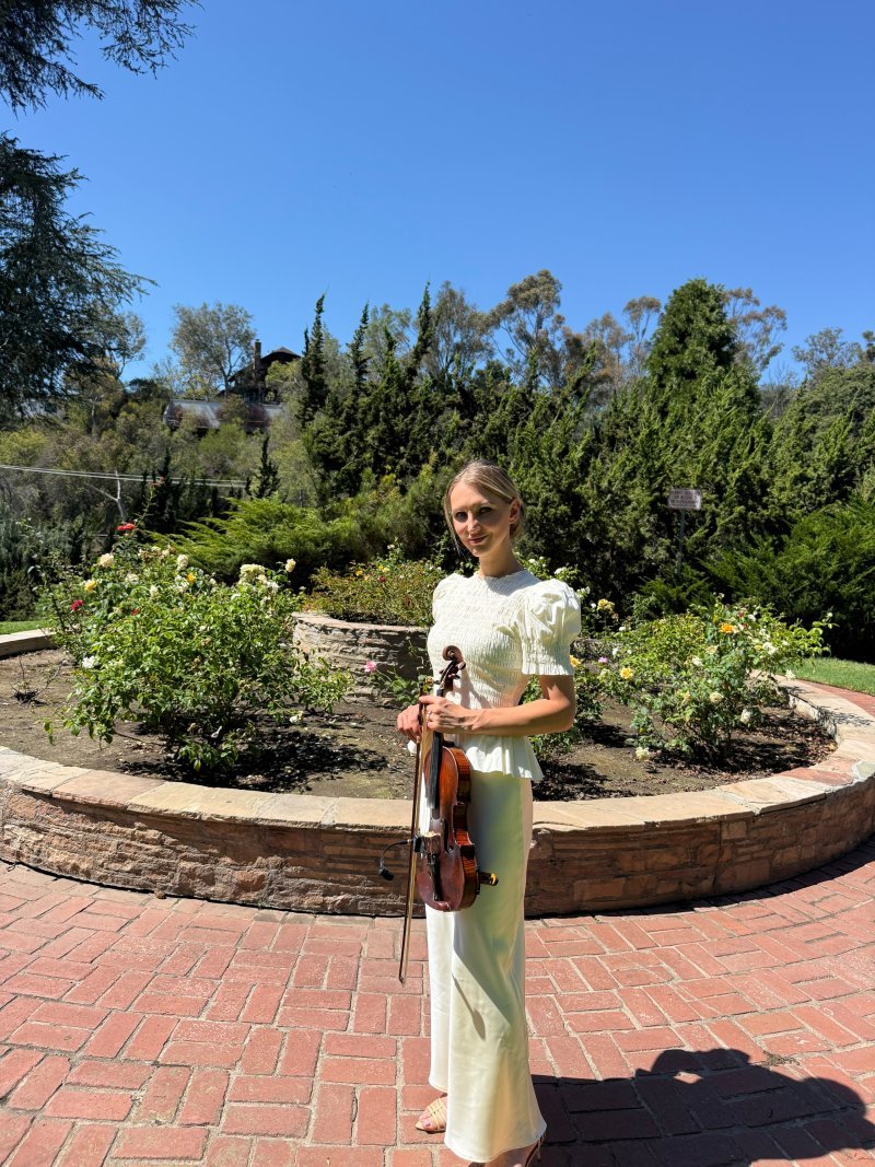 Mila with her violin in a rose garden