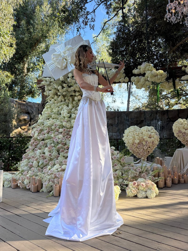 Violinist in a white gown performing at a wedding